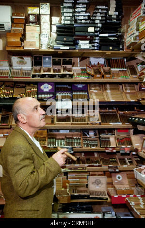 Tabacco maturo proprietario del negozio guardando i sigari sul display Foto Stock