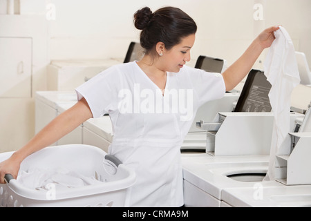Giovani lavoratrici di mettere i vestiti in lavatrice Foto Stock