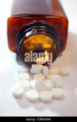 Compresse bianche fuoriuscita da una bottiglia di medicina Foto Stock