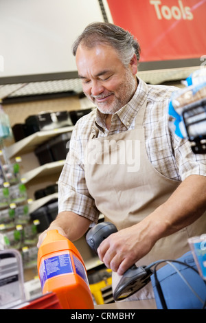 Felice coppia addetto alle vendite utilizzando il lettore di codici a barre al momento del checkout contatore nel contatore hardware Foto Stock