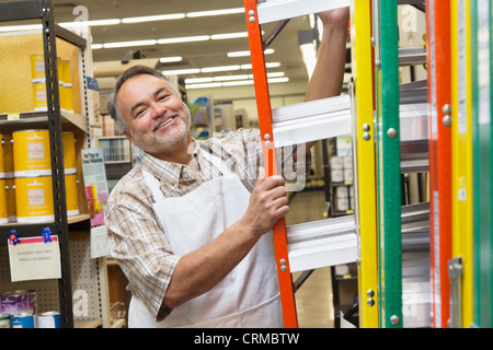 Ritratto di un felice uomo maturo con scaletta in negozio di ferramenta Foto Stock