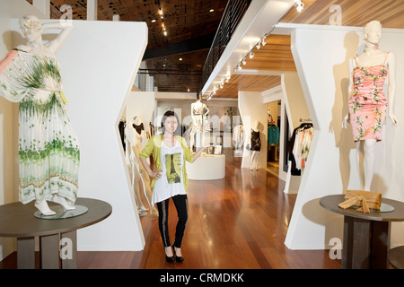 Ritratto di una bella metà donna adulta in piedi con manichini in boutique di moda Foto Stock