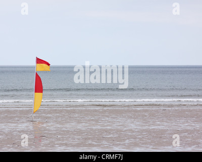 Rosso e giallo di bandiera sulla spiaggia di Westward Ho !, Inghilterra indicando una balneazione sicura e zona di surf sorvegliata da bagnini Foto Stock