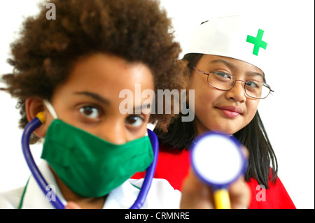 Il personale ospedaliero di domani? Un giovane ragazzo africano e una ragazza asiatica vestito come un medico e infermiere. Foto Stock