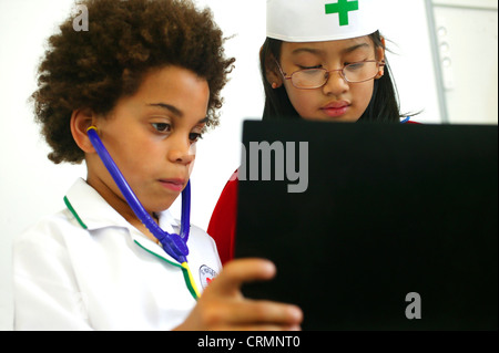 Il personale ospedaliero di domani? Un giovane ragazzo africano e una ragazza asiatica vestito come un medico e infermiere leggere le note sul paziente. Foto Stock