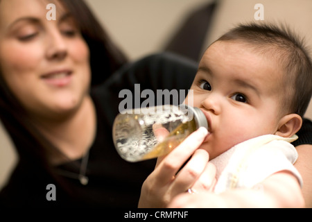 Una giovane madre bottiglia alimenta la sua bimba. Foto Stock