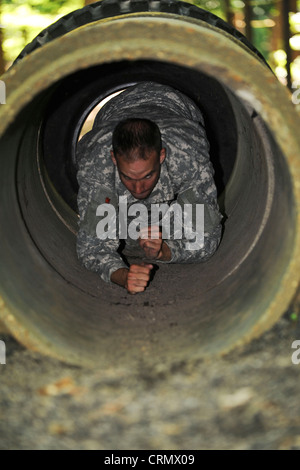 Esercito degli Stati Uniti Sgt. Jarod Moss, 95th Reserve Division drill sergeant, striscia attraverso l'ostacolo tunnel sul corso di fiducia a Fort Eustis, Va., come parte della competizione annuale Drill Sergeant of the Year, ospitato da Initial Military Training, U.S. Army Training and Dottrine Command, 27 giugno 2012. Durante il corso i concorrenti hanno dovuto fare cose come: Basso crawl, attraversare le barre delle scimmie, scalare le pareti e saltare fossati. Foto Stock