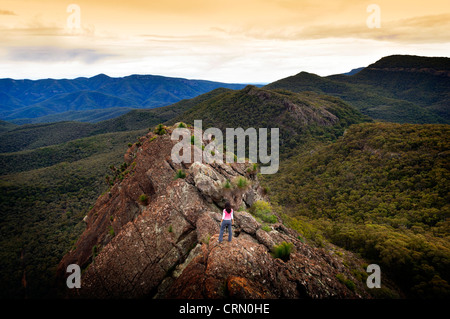 Unico giovane donna si affaccia con determinazione in cima a una montagna Foto Stock