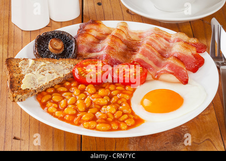 La completa prima colazione inglese su un vecchio pino tavolo da cucina. Foto Stock