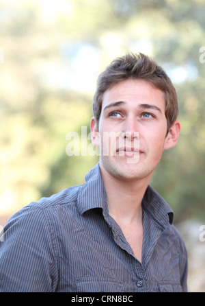 Casual bel giovane uomo sorridente leggermente mentre all'aperto Foto Stock