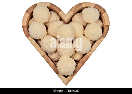 Candy in una scatola di legno a forma di cuore isolato su sfondo bianco. Close-up, vista dall'alto. Foto Stock