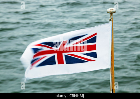 Union Jack flag sbattimenti nel vento sulla prua di un piacere di Windermere lancio di crociera. Foto Stock