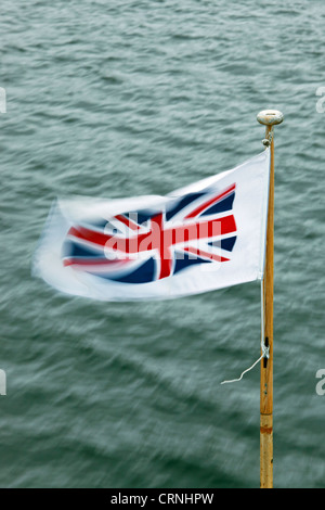 Union Jack flag sbattimenti nel vento sulla prua di un piacere di Windermere lancio di crociera. Foto Stock