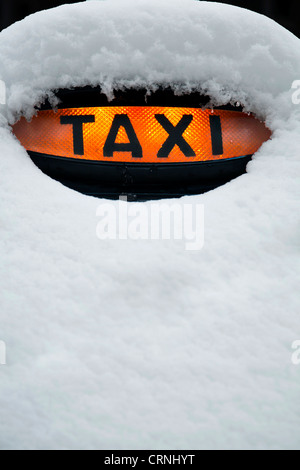 Londra taxi con noleggio di colore arancione in luce nella neve Foto Stock