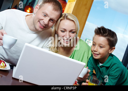 Famiglia di tre persone di essere stupito con la roba visualizzata sullo schermo del computer portatile Foto Stock