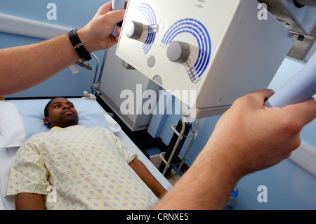 Un radiologo la preparazione di un paziente per examiantion al di sotto di una macchina a raggi x. Foto Stock