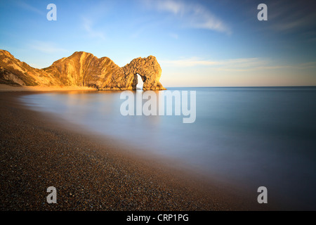 Il sole proietta una luce calda sulla porta di Durdle, una pietra calcarea naturale arch nelle vicinanze Lulworth Cove, parte dell'UNESCO Jurassic Coast. Foto Stock