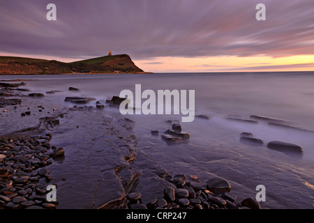 Vista su sporgenze rocciose nella baia di Kimmeridge verso Clavell Tower, stile toscano torre costruita nel 1830 sulla scogliera di gallina su Giurassico Foto Stock