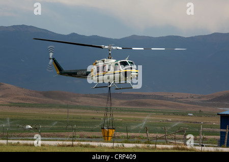 Elicottero foresta di antenna di combattimento aereo della benna di riempimento con acqua dal laghetto per caduta sulle fiamme e hot spot. Foto Stock