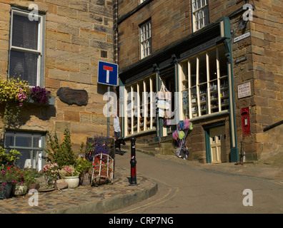 Una donna che cammina il suo cane giù King Street nel villaggio di pescatori di Robin Hood's Bay, una volta che il più trafficato della comunità di contrabbando sul Foto Stock