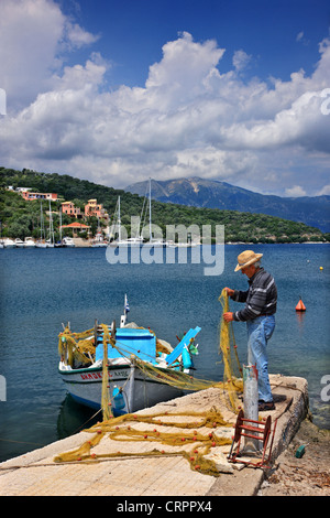 Vecchio Pescatore rammendo il suo net presso il piccolo porto di Vathi, Meganisi (isola di Lefkada Prefettura), Mare Ionio, Eptanisa, Grecia Foto Stock