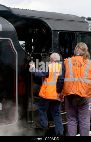 Due i lavoratori del settore ferroviario entrare nella cabina di un treno a vapore in Scozia Foto Stock