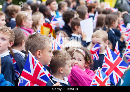 La scuola dei bambini ondata la torcia olimpica attraverso Ambleside nel distretto del lago, UK. Foto Stock