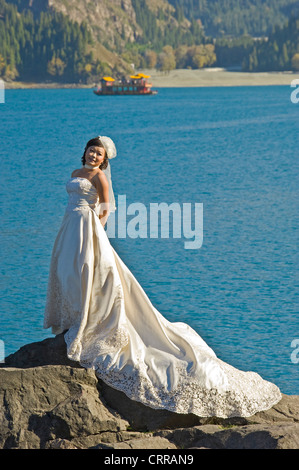 Una sposa cinese comporta per il suo matrimonio fotografie presso la popolare alpine beauty spot del lago celeste. Foto Stock