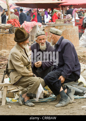 Anziani cinese uigura uomini in abiti tradizionali al mercato locale nella piccola cittadina di Upal, Cina. Foto Stock