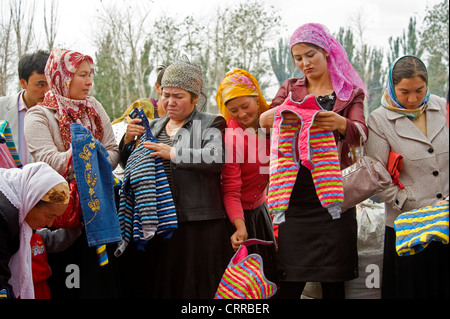 Uyghur le donne cinesi acquistare vestiti per bambini al mercato locale nella piccola cittadina di Upal, Cina. Foto Stock