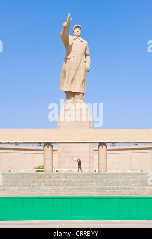 Un turista è sopraffatte come fotografa la statua dell ex leader cinese Mao Zedong di fronte alla piazza della città di Kashgar. Foto Stock