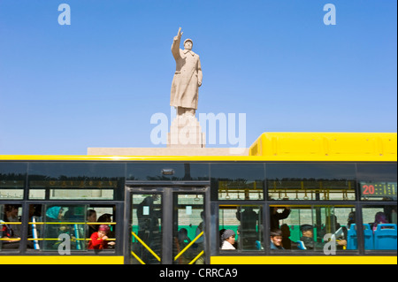 Con motion blur. Un autobus pubblico viaggia dopo la statua di Mao Zedong di fronte alla piazza della città di Kashgar. Foto Stock