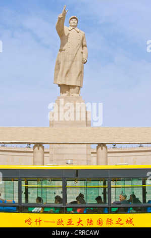 Con motion blur. Un autobus pubblico viaggia dopo la statua di Mao Zedong di fronte alla piazza della città di Kashgar. Foto Stock