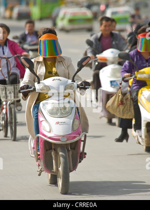 Una compressa di vista prospettica di persone su scooter che viaggia lungo una strada principale di Kashgar. Foto Stock