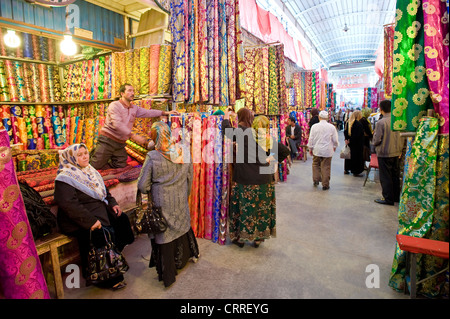 Uyghur popolo cinese e coloratissimi rotoli di tessuto di seta in Asia Western-Central mercato () Bazaar di Kashgar. Foto Stock