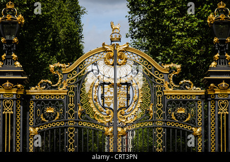 Canada Gate Green Park Royal Arms Londra Estate | LONDRA — Le opere in ferro dorate al Canada Gate nel Green Park mostrano le Royal Arms sotto un leone incoronato, incorniciate da alberi verso Buckingham Palace. Offerte dal Canada come parte del progetto del Victoria Memorial completato nel 1911, è una delle sei porte donate dalle nazioni del Commonwealth per celebrare il regno della regina Vittoria. Foto Stock