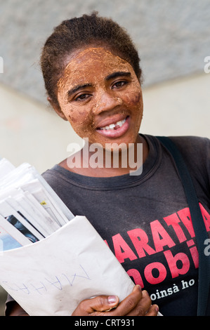 Giovane donna con vernice faccia vendere giornali, Mahajanga, Madagascar Foto Stock