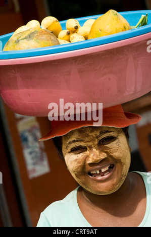 Donna con la faccia la vernice per la vendita di frutta, Mahajanga, Madagascar Foto Stock