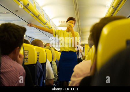 Equipaggio di cabina a bordo di un volo Ryanair in dimostrazione di sicurezza che mostra l'utilizzo di maschere di ossigeno Foto Stock