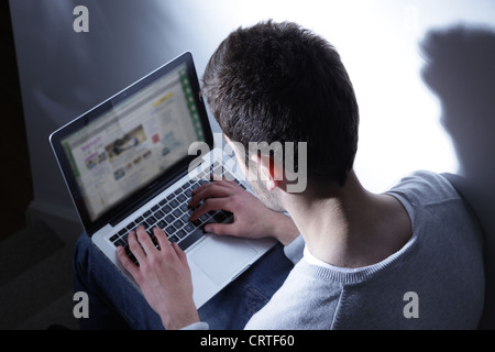 Giovane maschio usando il suo computer portatile su Yahoo home page. Foto Stock
