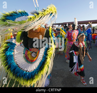 Fort Washakie, Wyoming - Giovane partecipante in un powwow controllo della regalia di un adulto ballerina durante l'Indiano giorni. Foto Stock