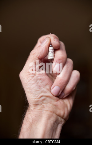 La depressione con in mano un bicchiere di stricnina ampolla di veleno in mano tra il pollice e il dito la malattia mentale mente morte Foto Stock