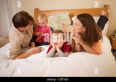 Padre, madre e due figli sono sdraiato sul letto. Foto Stock