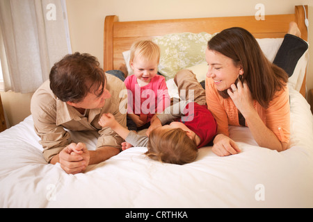 Padre, madre e due figli sono sdraiato sul letto. Foto Stock