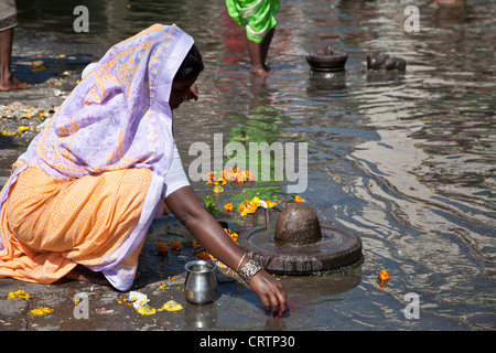 Donna fare un rituale di fiume offrendo (puja). Fiume Godavari. Nasik. India Foto Stock