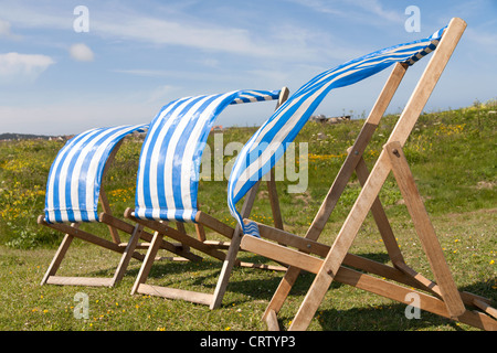 Tre blu e bianco sdraio in una fila al vento, Guernsey Foto Stock