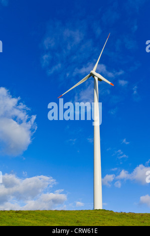 Le turbine eoliche in una fattoria eolica sulla cima di una collina contro un cielo blu Foto Stock