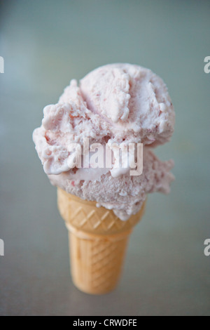 Un grande scoop di gelato alla fragola su una torta a cono. Foto Stock