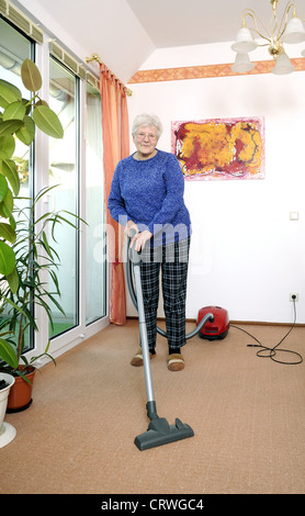 Donna anziana con aspirapolvere Foto Stock