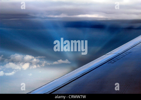 Raggi del sole formando una vista mozzafiato tra le nuvole come visto da un aereo finestra. Foto Stock